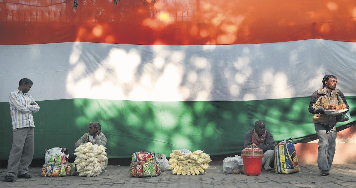 Indian vendors wait for customers near an Indian national flag, New Delhi, India, Dec. 28. 