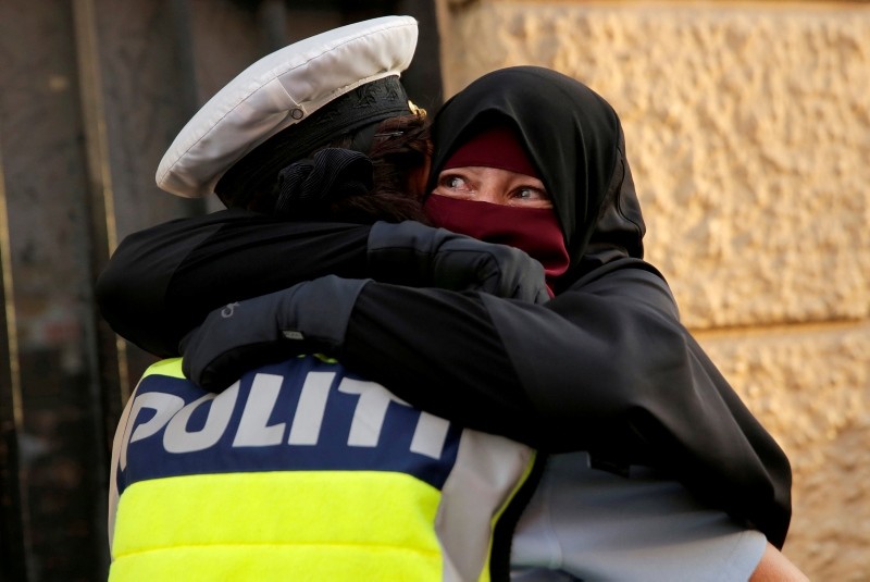 Ayah, 37, a wearer of the niqab weeps as she is embraced by a police officer during a demonstration against the Danish face veil ban in Copenhagen, Denmark, August 1, 2018. (Reuters Photo)