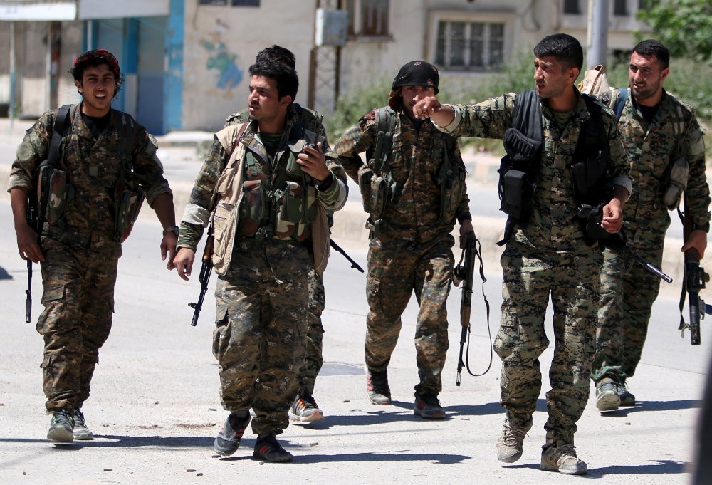 YPG terrorists walk along a street in the southeast of Qamishli city, Syria, April 22, 2016. 