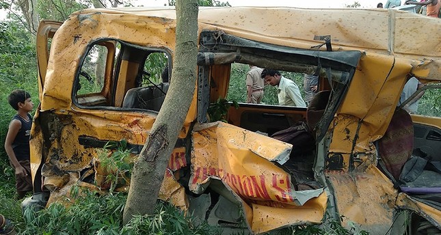 Onlookers gather around the mangled remains of a school bus after it was hit by a train in Kushinagar district in India's Uttar Pradesh state on April 26, 2018. (AFP Photo)