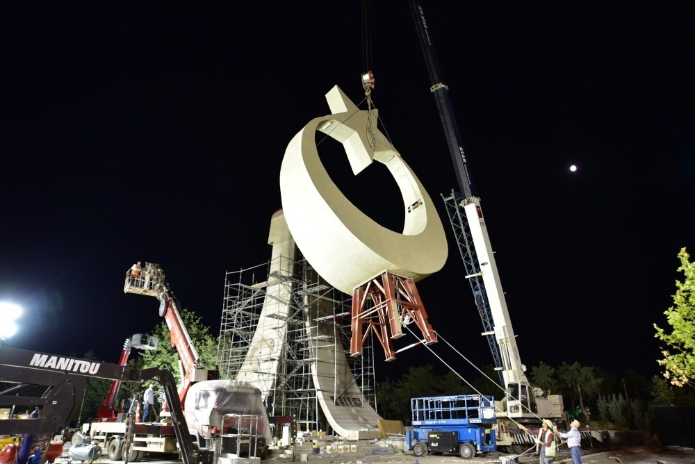 Workers install the crescent and star symbols of the Turkish flag on top of a monument dedicated to coup victims which was built across the street of presidential palace.