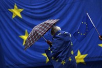 A participant wrapped in a European flag protects herself from the rain during the monthly pro-European Union rally titled, 'Pulse of Europe,' in Berlin, Germany, Nov. 25. 
