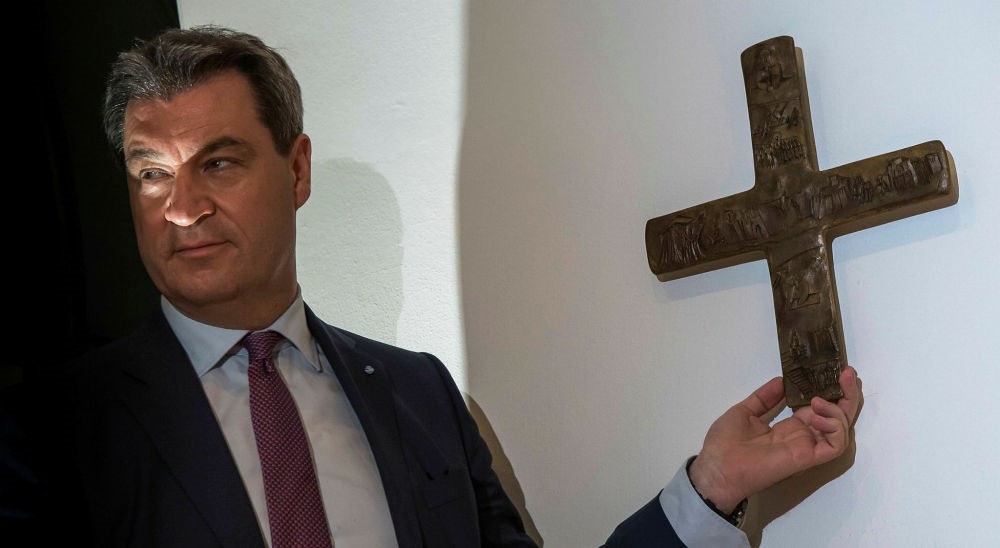 Markus Soeder, Bavarian State premier, hangs a cross in the entrance area of the Bavarian State Chancellery, Munich, April 24.