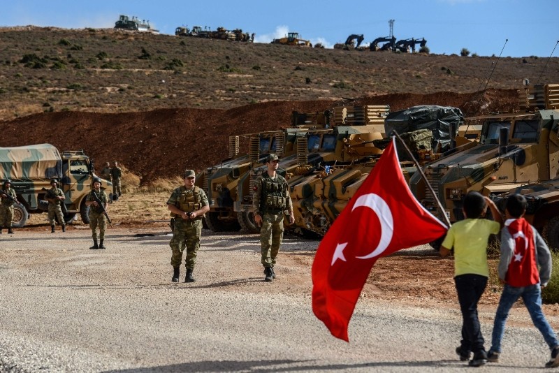 Turkish soldiers stand near armored vehicles as two young boys holding Turkish flags arrive during a demonstration in support of the Turkish Armyu2019s Idlib Operation. (AFP Photo)