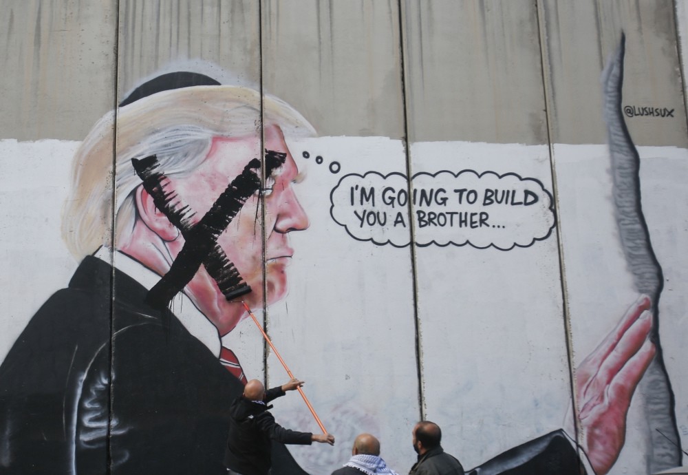 A Palestinian paints over a mural of President Trump during a protest in Bethlehem, West Bank, Dec. 7.
