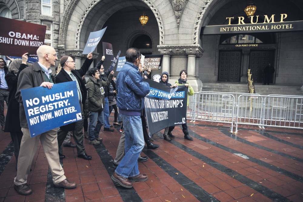 People protest the then U.S. presidential candidate Donald Trump's campaign pledge to register Muslims in the country, in front of his hotel in Washington D.C.