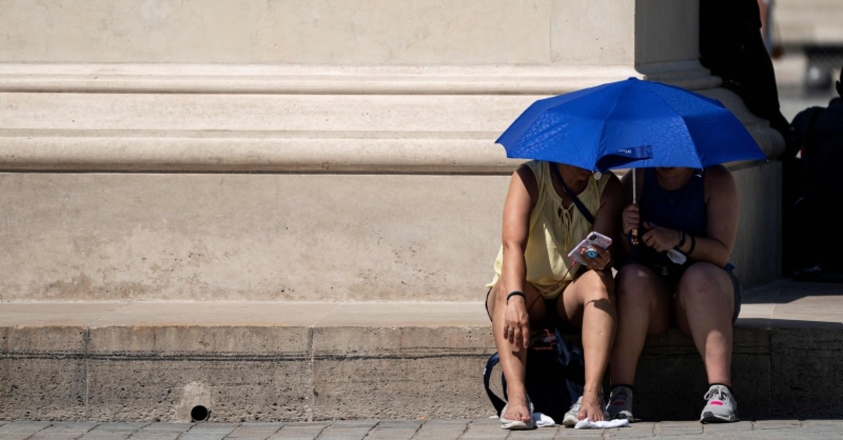 People use an umbrella to shelter from the sun near the Louvre Pyramid (Pyramide du Louvre) during a heatwave in Paris on June 26, 2019. (AFP Photo)