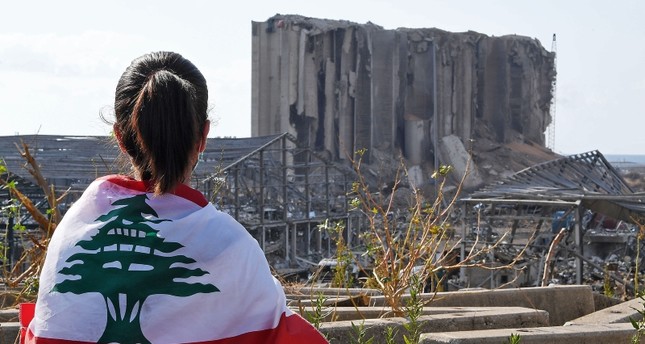 فتاة ملفحة بعلم لبنان تنظر إلى مكان انفجار الميناء الفرنسية