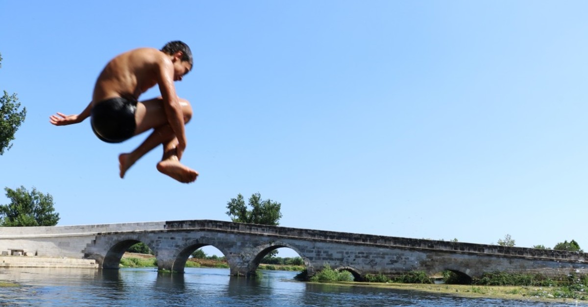 Children jump into a stream in Antalya where temperatures soared to 31 Celsius degrees, June 24, 2019.