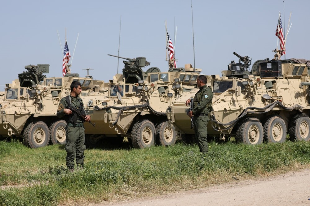 People's Protection Units (YPG) terrorists stand near U.S. military vehicles in the town of Darbasiya next to the Turkish border, April 29, 2017.