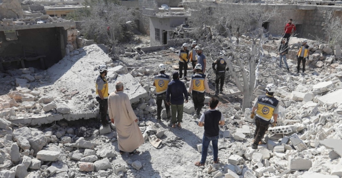 Members of the Syrian Civil Defence (White Helmets) and civilians gather following a reported regime airstrike on the village of Kafriya, in Syria's Idlib province, on July 13, 2019. (AFP Photo)
