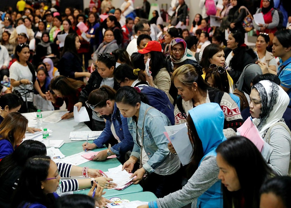 Filipino household workers who were repatriated from Kuwait show their documents as they arrive at Manila's international airport, Philippines, 21 February 2018. (EPA Photo)