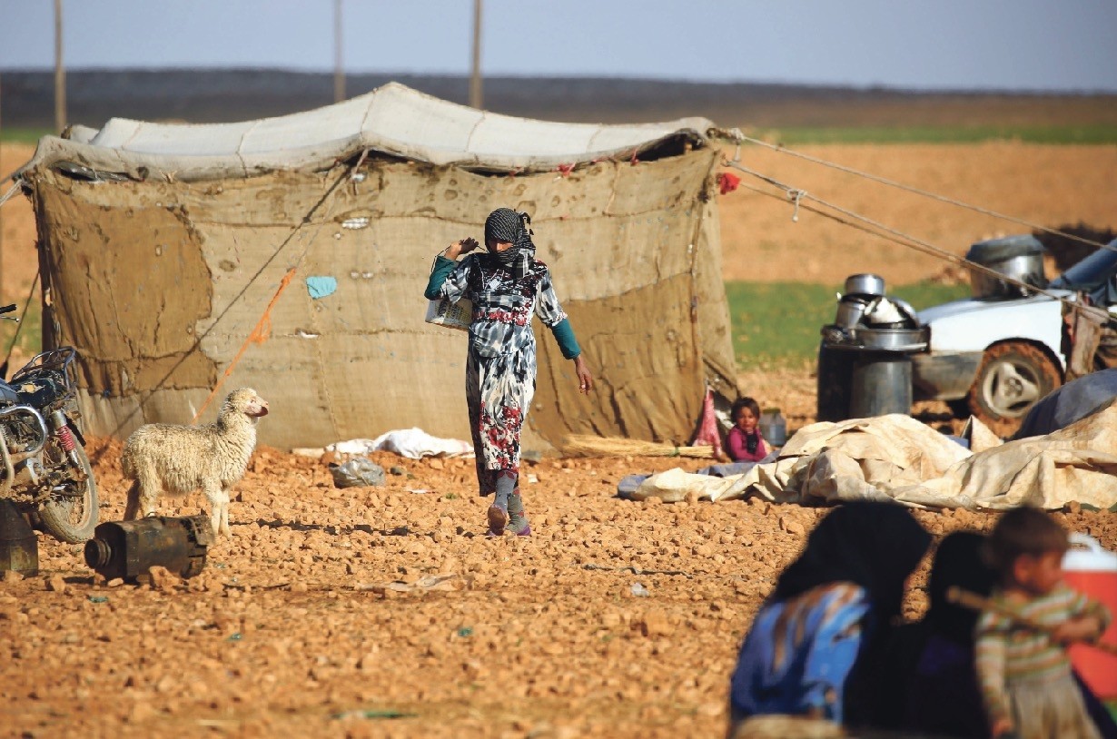 A displaced Syrian woman walking at a makeshift camp in the village of Jab al-Tur, also known as Ukuz Quy, on the southern outskirts of Manbij, March 7. 