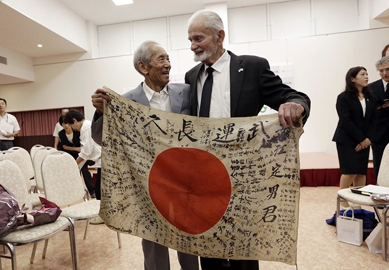 WWII veteran Marvin Strombo (R) and Tatsuya Yasue, 89-year-old farmer, hold a Japanese flag with autographed messages which was owned by his deceased brother Sadao Yasue, during a ceremony in central Japan's Gifu prefecture, Aug. 15, 2017. (AP Photo)