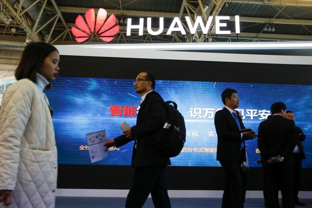 People walk past the stall of Huawei Technologies at the Security China 2018 exhibition on public safety and security in Beijing, Oct. 23.