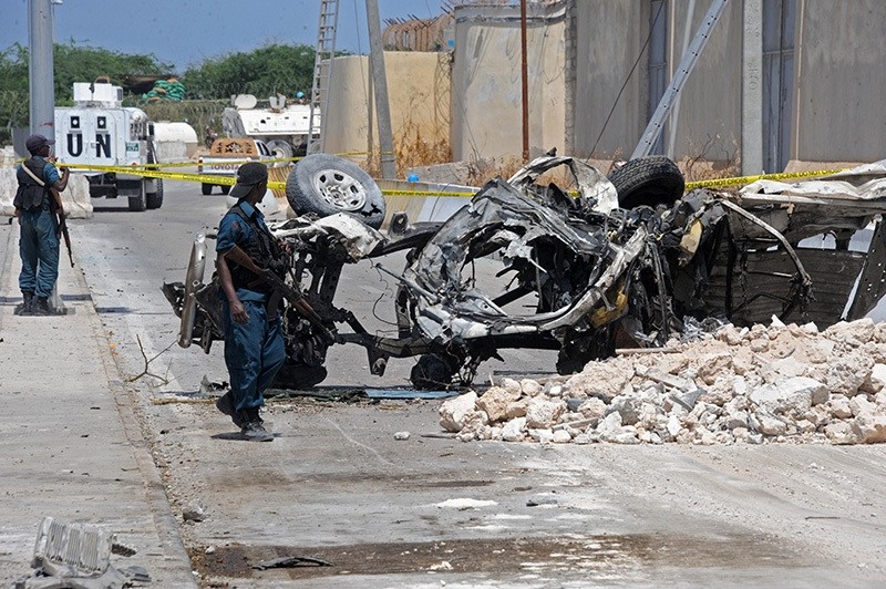 omali soldiers pass near the wreckage of a car bomb outside the UN's office in Mogadishu on July 26, 2016. (AFP Photo)