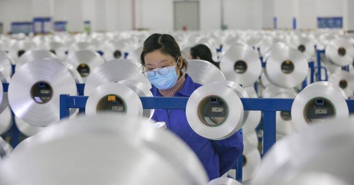 A Chinese employee wearing a face mask produces material used in making protective suits at a textile factory in Nantong, China's eastern Jiangsu province. (AFP Photo)