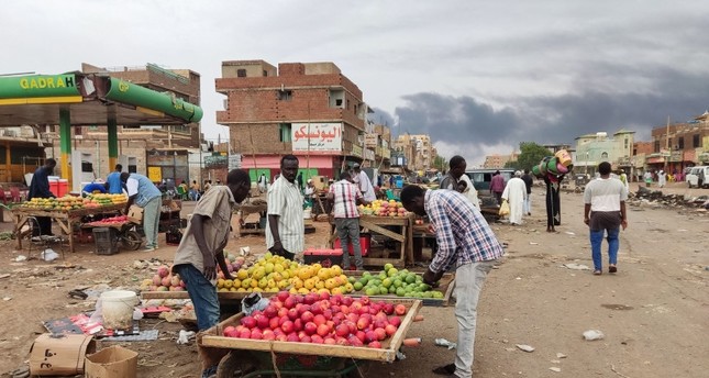 الدخان يتصاعد فوق المباني مع تجمع الناس في سوق لشراء المؤن الغذائية، في الخرطوم مع بدء سريان وقف إطلاق النار لمدة 24 ساعة 10-6-2023 صورة : AFP