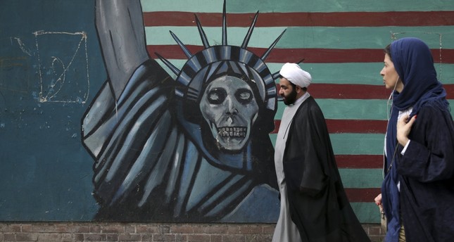 A cleric and a woman walk past an anti-U.S. mural painted on the wall of the former U.S. Embassy in Tehran.