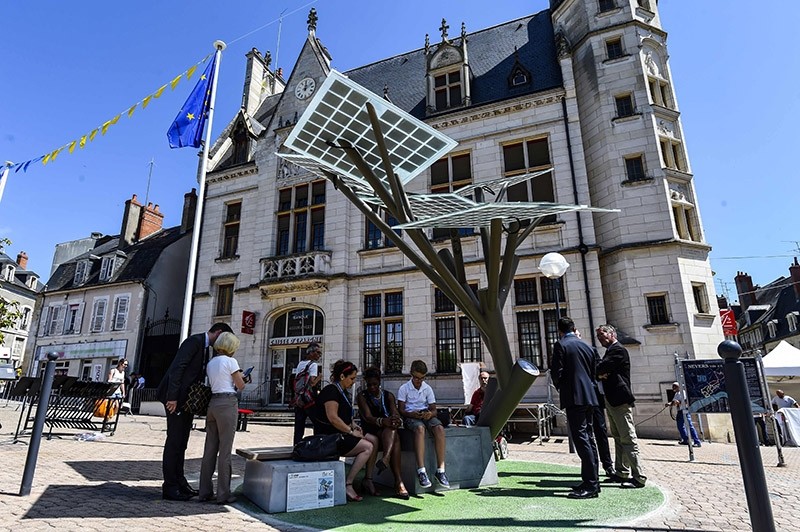 People try to connect their smart-phones to the first ,eTree, provided in Europe by Solar Tree Europ, a French-Israeli start up, on May 29, 2017 (AFP Photo)