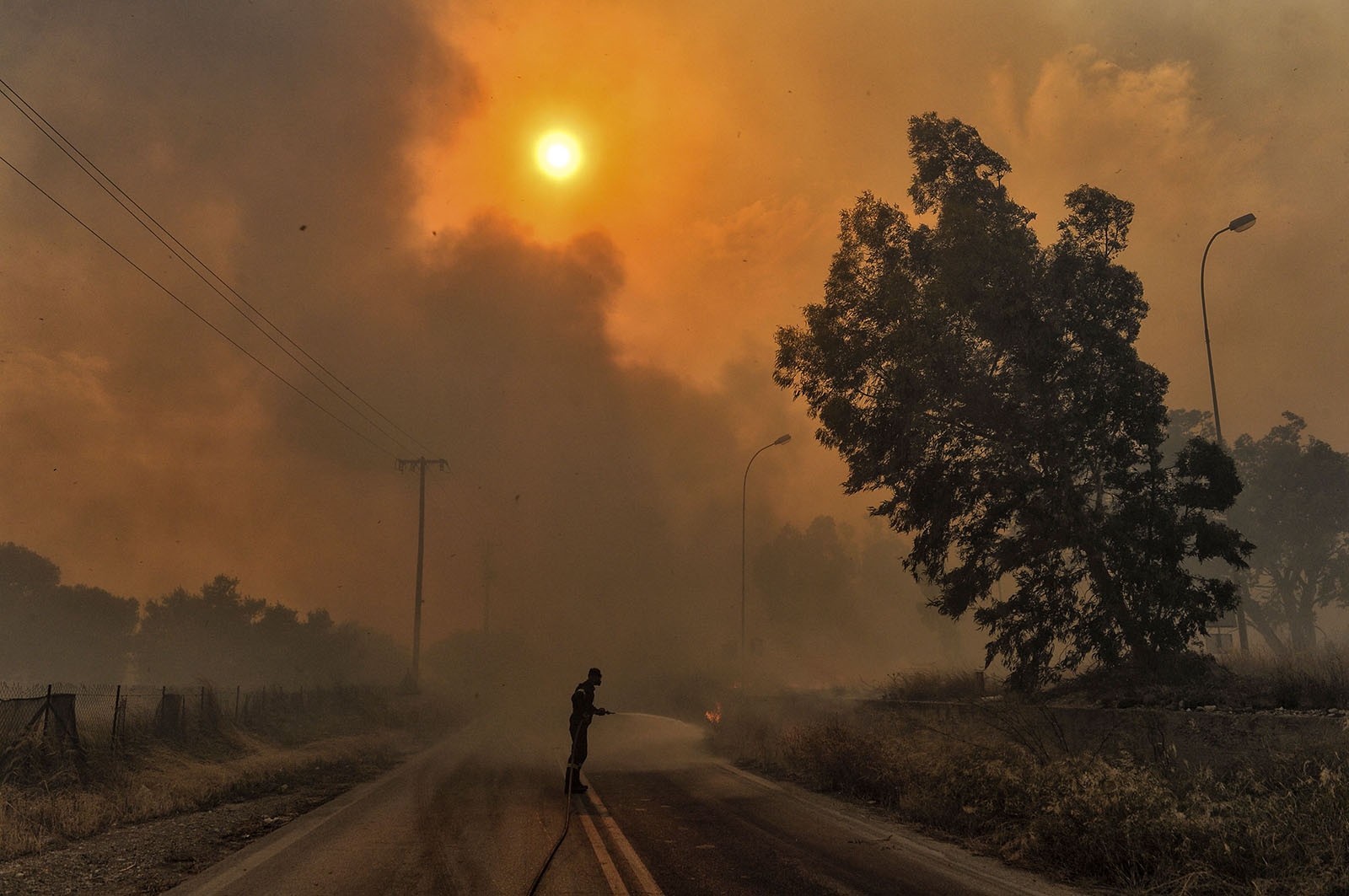 A firefighter tries to extinguish hotspots during a wildfire in Kineta, near Athens, on July 23, 2018. 