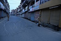 An Indian paramilitary soldier unfolds barbed wire to block a road during restrictions in Srinagar, Kashmir, Sept. 27, 2019. 