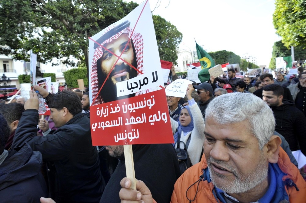 Tunisian protesters holding placards in Arabic that read ,Tunisians against the Saudi crown prince's visit,, shout slogans during a demonstration in Tunis, Nov. 27.