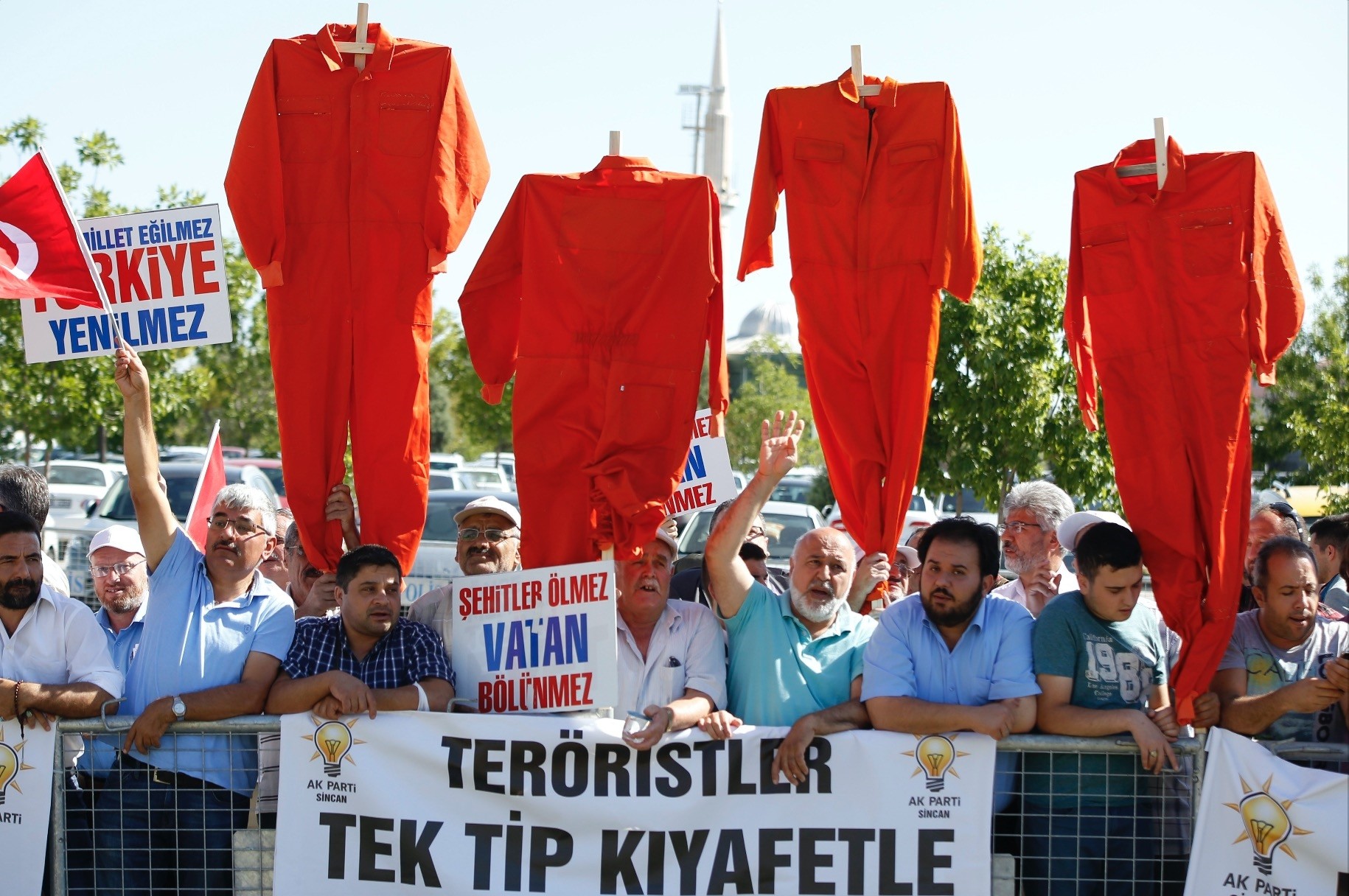 Protesters brandish orange jumpsuits as defendants in a major coup trial in Ankara are being brought to the court for trial on Aug. 1.