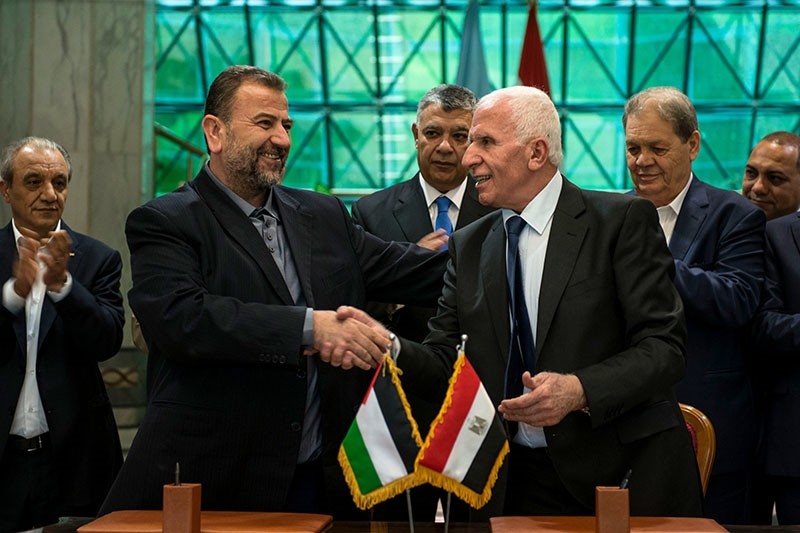 Fatah Central Committee member Azam al-Ahmed (R), shakes hands with Saleh al-Aruri (L), Hamas deputy head of the politburo, as Egypt's Intelligence Minister Khalid Fawzi (C, back) looks on after signing a deal, in Cairo, Egypt, Oct. 12, 2017. (EPA)