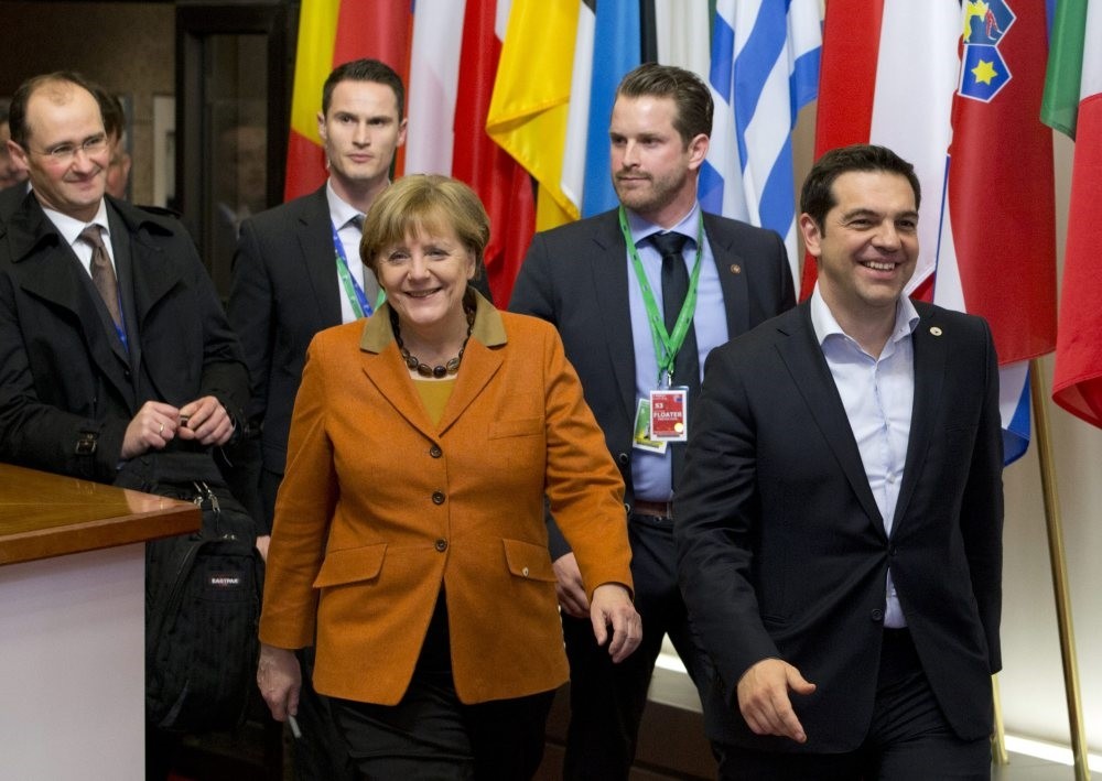 Greek Prime Minister Alexis Tsipras, right, walks with German Chancellor Angela Merkel, center, as they leave an EU summit in Brussels.