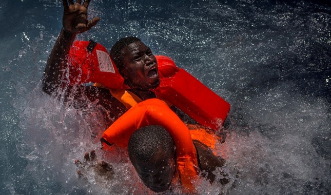 Two men panic and struggle in the water during their rescue. Their rubber boat was in distress and deflating quickly on one side, tipping many migrants in the water. They were quickly reached by rescue swimmers and brought to safety. (EPA Photo)