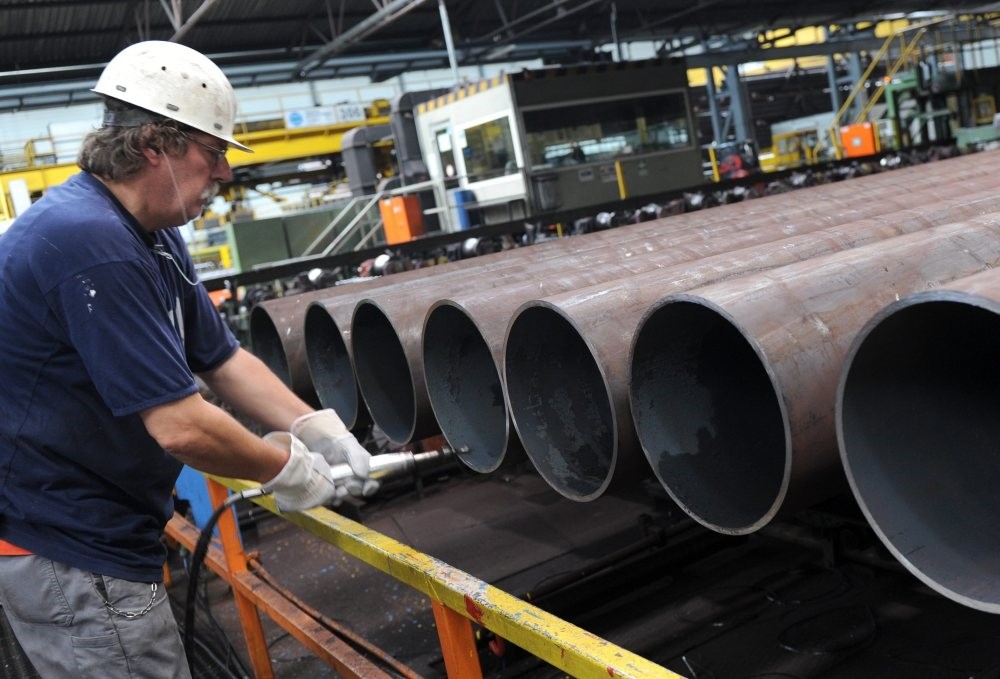 An employee checks a steel pipe in the manufacturing hall at Vallourec and Mannesmann in Duesseldorf, Germany, July 9, 2013.