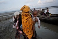 In this Sept. 21, 2017 photo, a Rohingya woman carries a child after crossing a stream on a small boat near Cox's Bazar's Dakhinpara area, Bangladesh. (AP Photo)