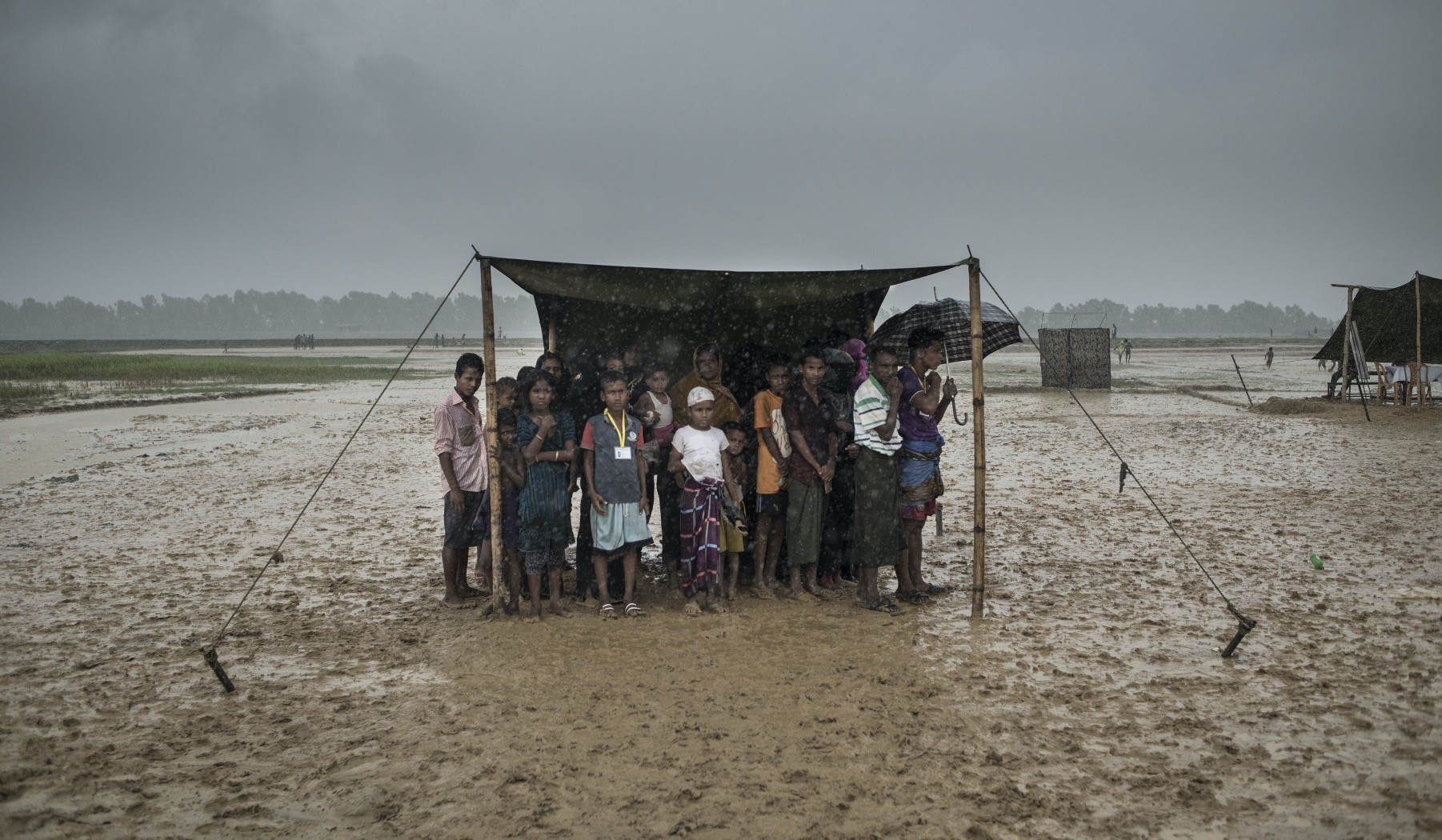 Rohingya Muslim refugees take shelter from the rain during a food distribution, Nayapara refugee camp, Ukhia, Bangladesh, Oct. 6, 2017.