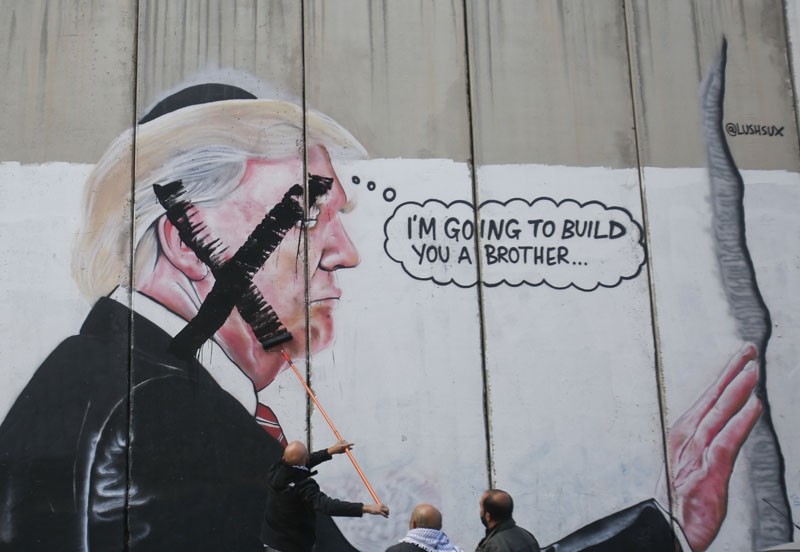 A Palestinian paints over a mural of President Trump during a protest in Bethlehem, the West Bank, Dec. 7, 2017. (AP Photo)