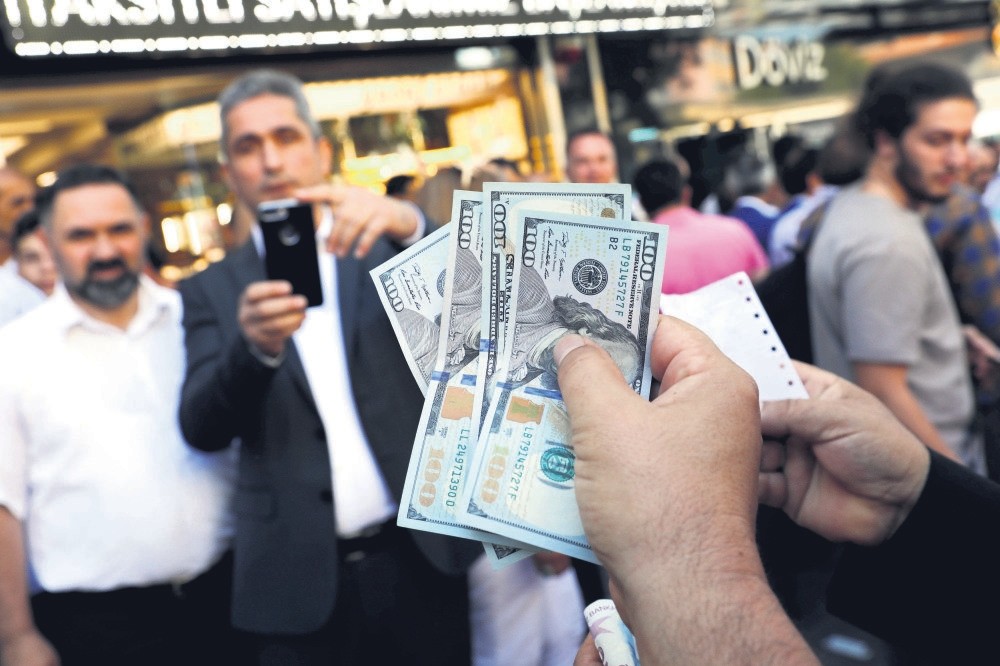 A businessman holding U.S. dollars poses for his friend in front of a currency exchange office in response to President Erdou011fan's call on Turks to sell their dollar savings to support the Turkish lira, Ankara, Aug.14.