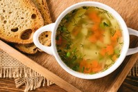 Chicken soup in a white bowl on a wooden tray. (iStock Photo)