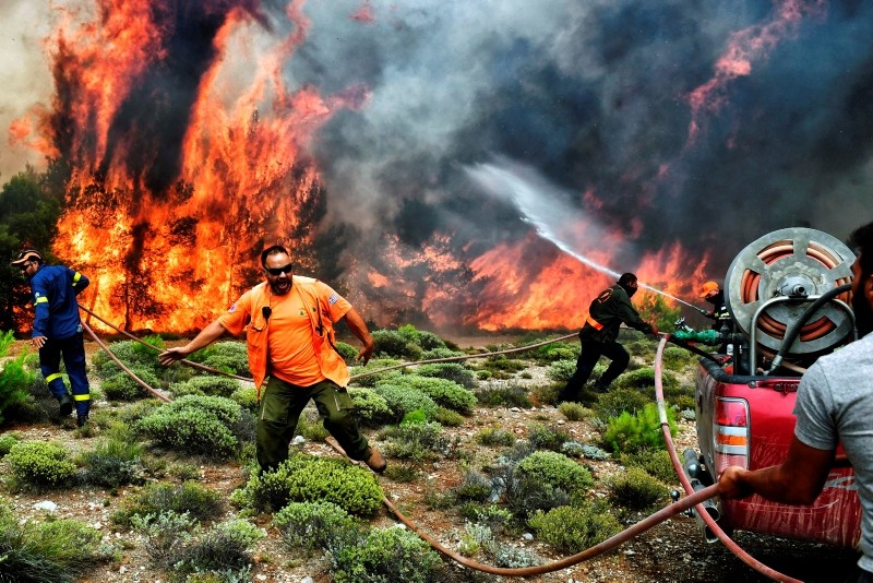 Firefighters and volunteers try to extinguish flames during a wildfire at the village of Kineta, near Athens, on July 24, 2018. (AFP Photo)