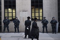 Orthodox Jewish men pass New York City police guarding a Brooklyn synagogue, New York, Dec. 11, 2019. (AP Photo)