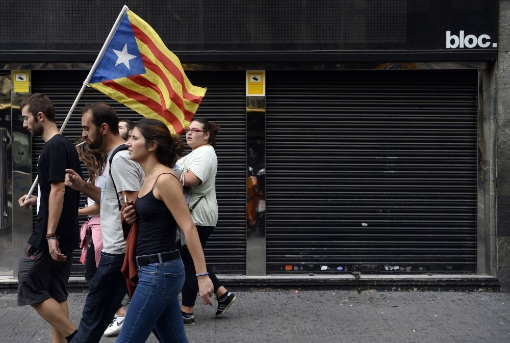 People walk past a closed store during a general strike called by Catalan unions in Barcelona. More than 2,700 companies including small and medium enterprises have moved their headquarters out of Catalonia and the list continues to grow. 