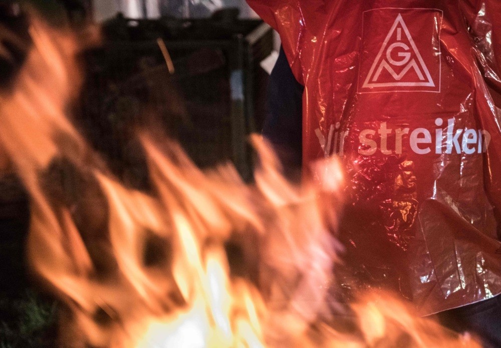 An employee of the Mercedes-Benz company wears a jacket of the metalworkers' and electrical industry union (IG Metall) with a slogan reading, ,We're on strike,, Berlin.