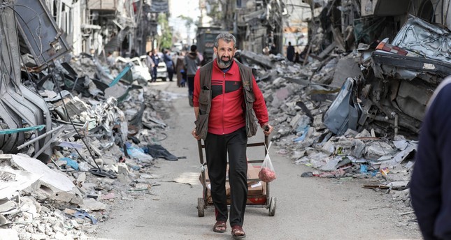 مواطنون فلسطينيون وسط مبان مدمرة في قطاع غزة صورة: الأناضول