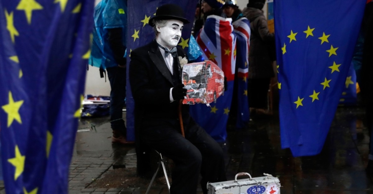Anti-Brexit remain in the European Union supporters take part in a protest under a heavy rain outside the House of Parliament in London, Tuesday, March 12, 2019. (AP Photo)