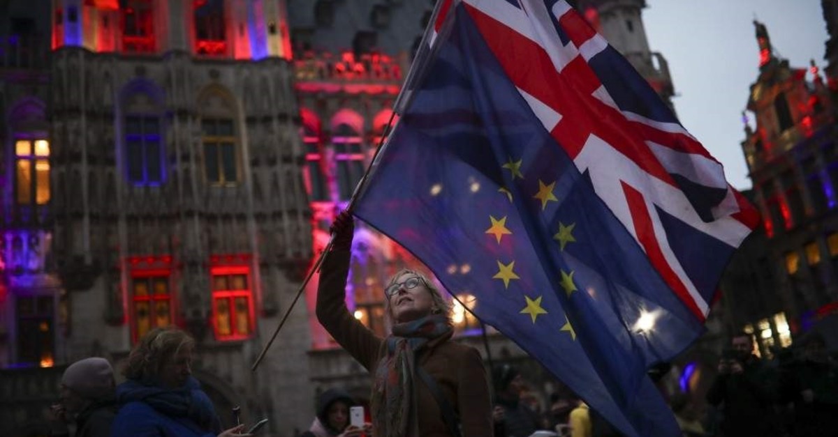A woman holds up the British and the European Union flags during an event called ,Brussels calling, to celebrate the friendship between Belgium and Britain at the Grand Place in Brussels, Thursday, Jan. 30, 2020. (AP Photo/Francisco Seco)