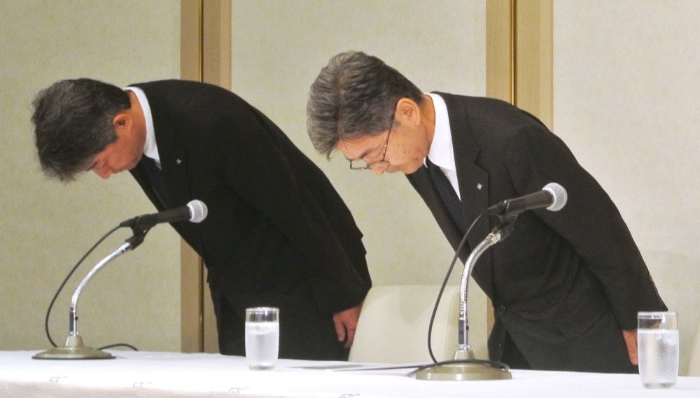 Kobe Steel's Executive Vice President Naoto Umehara (R) bows his head to apologize at a news conference in Tokyo.