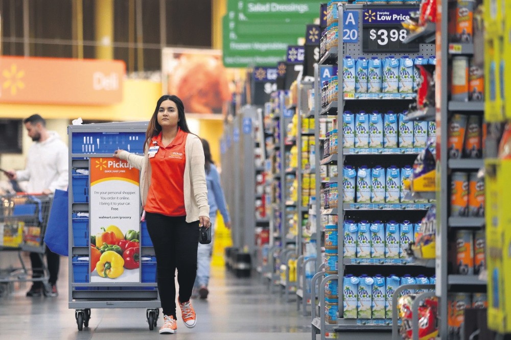 Laila Ummelaila, a personal shopper at Walmart in Old Bridge, N.J., pulls a cart with bins as she shops for online shoppers. Personal shoppers collect items for online orders and greet customers at a pickup location in the parking lot.