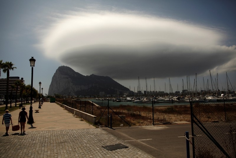 People walk along a street in front of the Rock of the British territory of Gibraltar (rear), a monolithic limestone promontory, next to the border in La Linea de la Concepcion, southern Spain Aug. 9, 2013. (Reuters Photo)