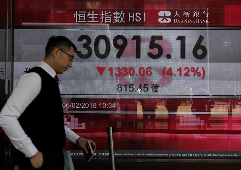 A man walks past a bank electronic board showing the Hong Kong share index at Hong Kong Stock Exchange Tuesday, Feb. 6, 2018. (AP Photo)