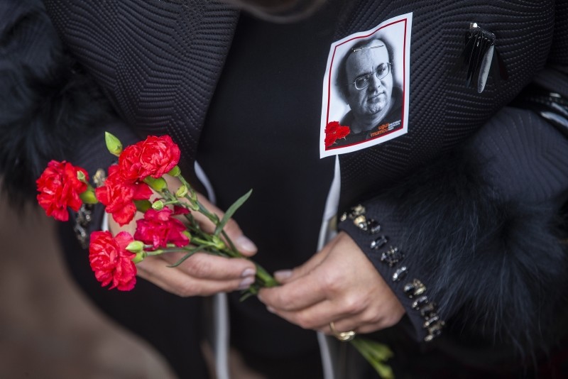A woman with a photo of journalist Uu011fur Mumcu pinned to her coat holds flowers during a commemorative ceremony on the 26th anniversary of his assasination, in Ankara, Turkey, Thursday, Jan. 24, 2018. (AA Photo)