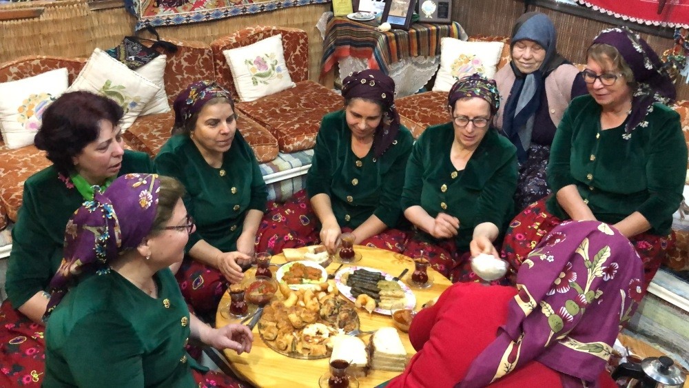Women in traditional cloths enjoy the meals they have prepared using their grandmothers' recipes.